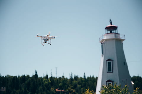 A drone in flight near a lighthouse with clear sky in the background HD wallpaper