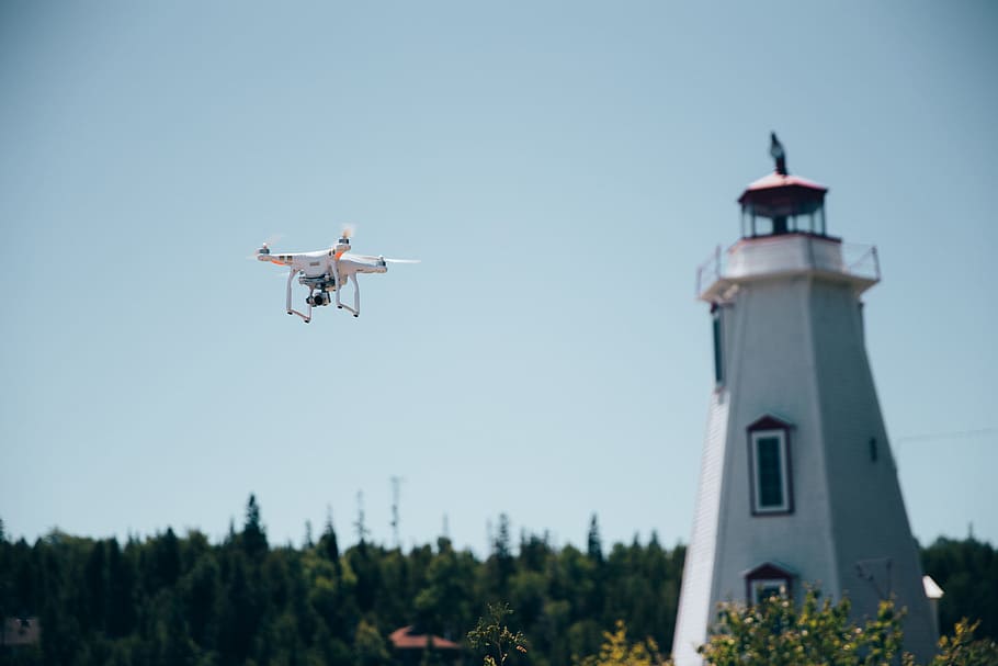 A drone in flight near a lighthouse with clear sky in the background