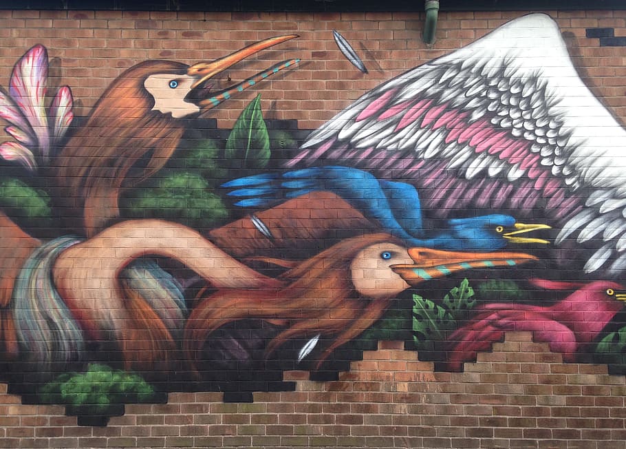 Mural of two birds attacking another bird on a brick wall in New Cross, Manchester.