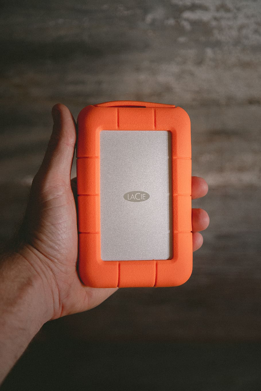 person holding rectangular orange and gray plastic case, human hand HD wallpaper