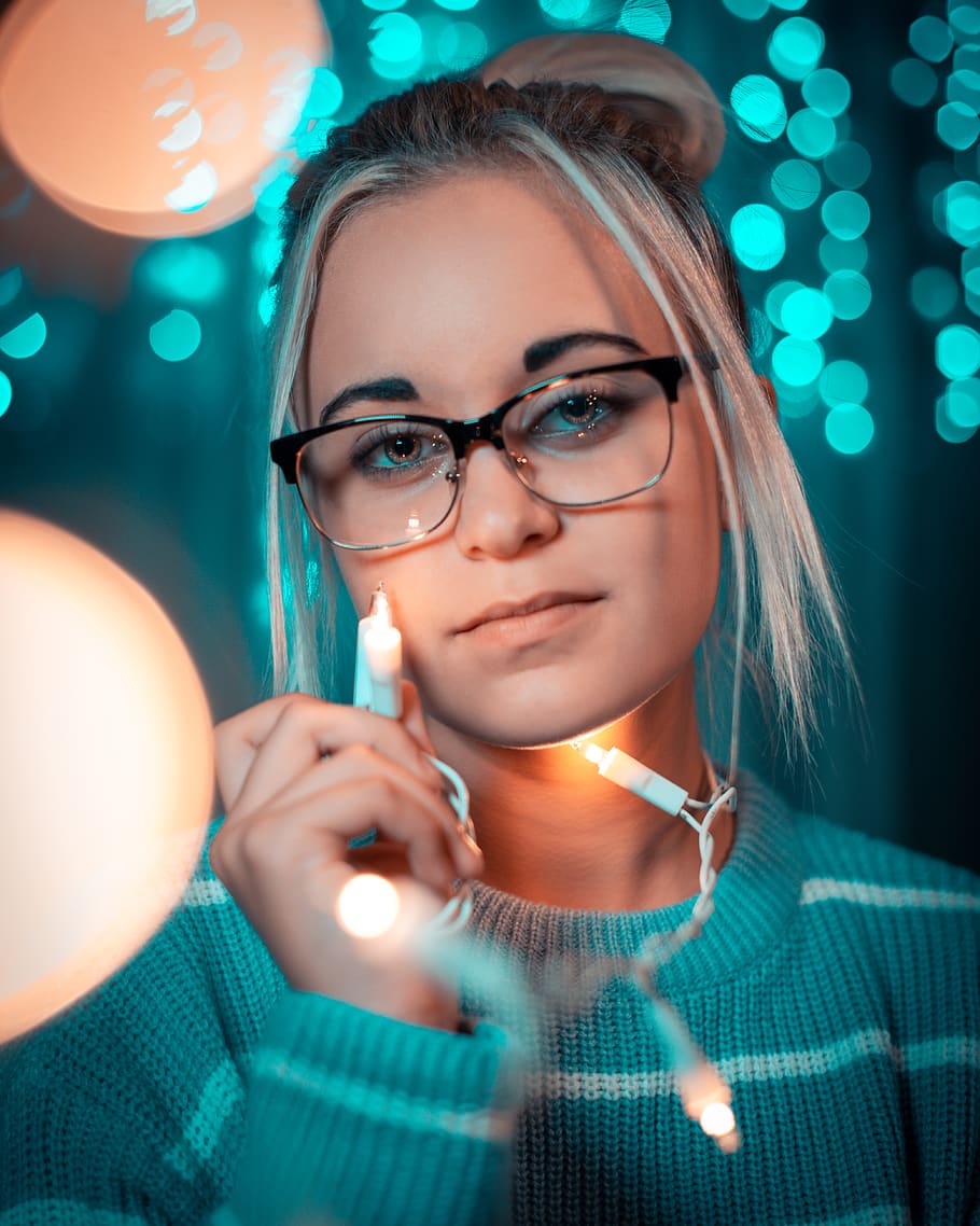 Woman Wearing Sweater Holding Christmas String Lights With Bokeh Background