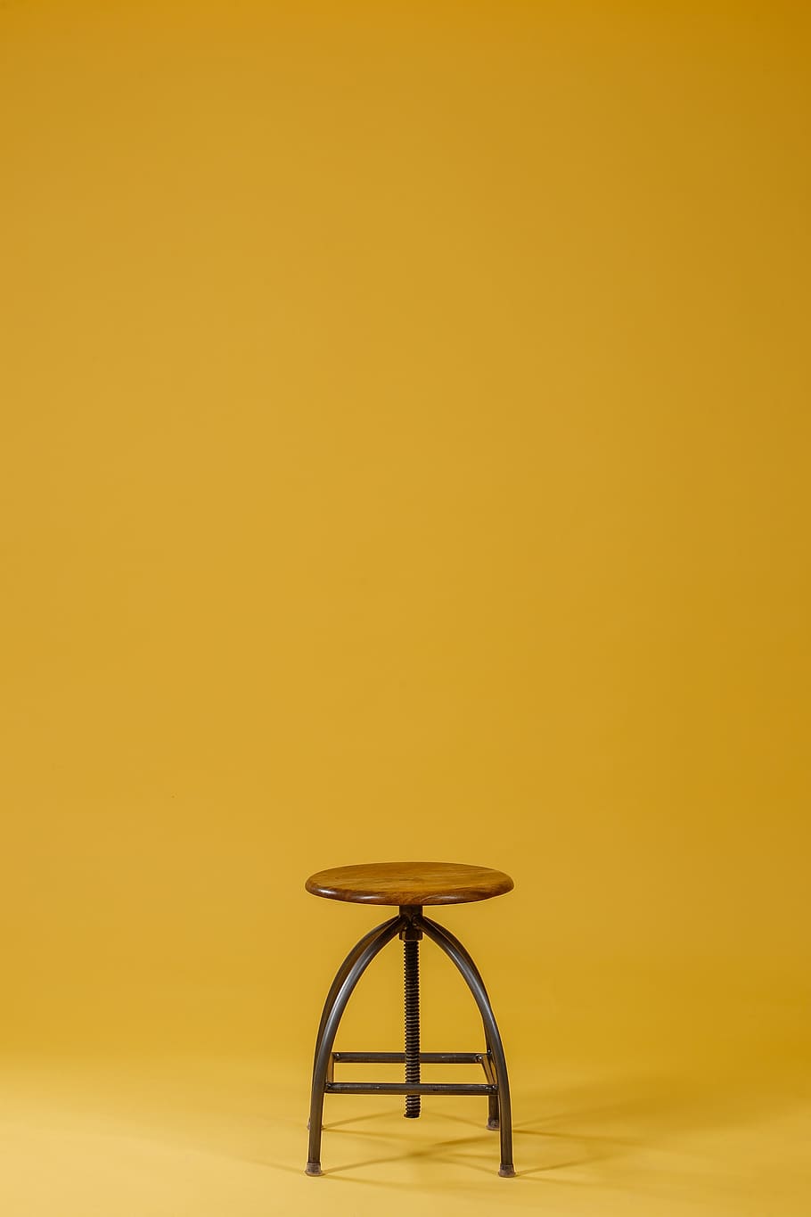 round brown wooden top and black base chair on yellow background, HD wallpaper