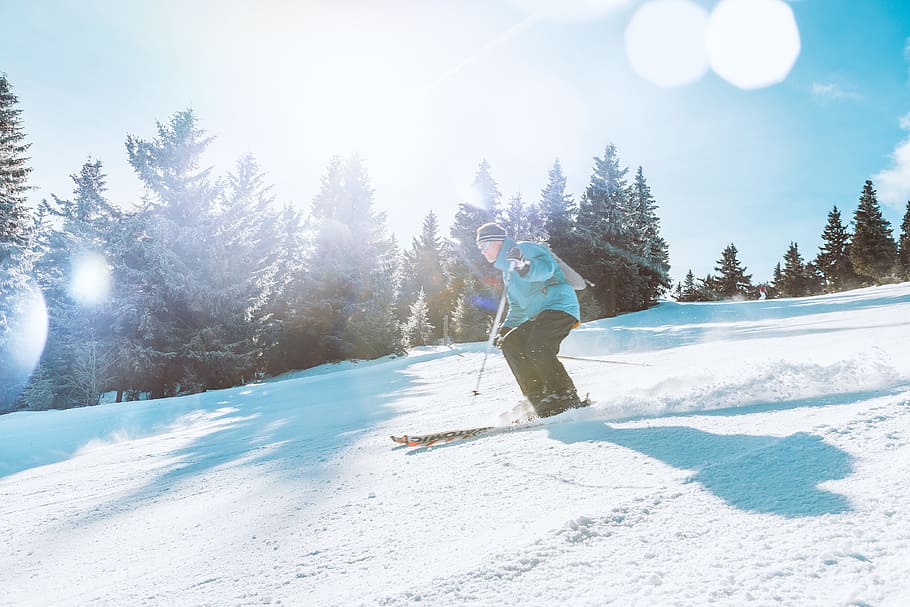 Skier skiing downhill during sunny day in high mountains, snow HD wallpaper