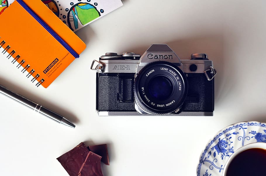 Gray and Black Canon Mirrorless Camera Beside Blue and White Ceramic Plate HD wallpaper