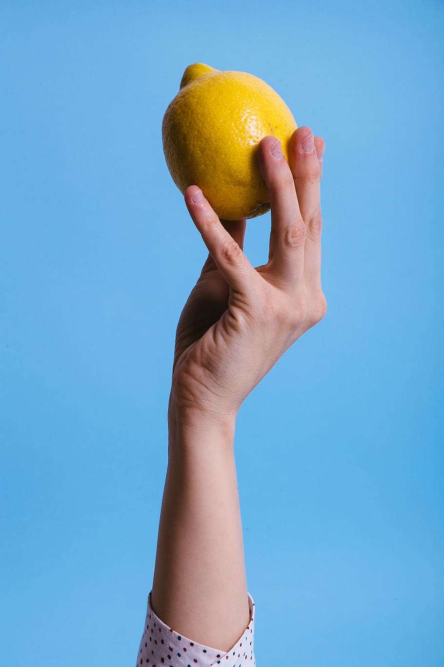 person holding lemon, hand, finger, fruit, citrus, yellow, blue