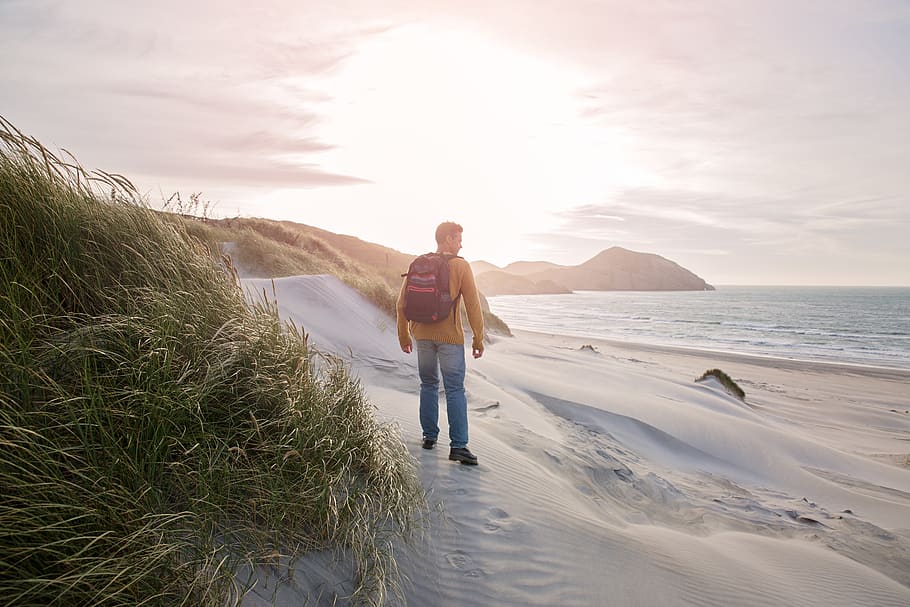 Man Carrying Black Backpack Standing on Seashore, beach, dawn HD wallpaper