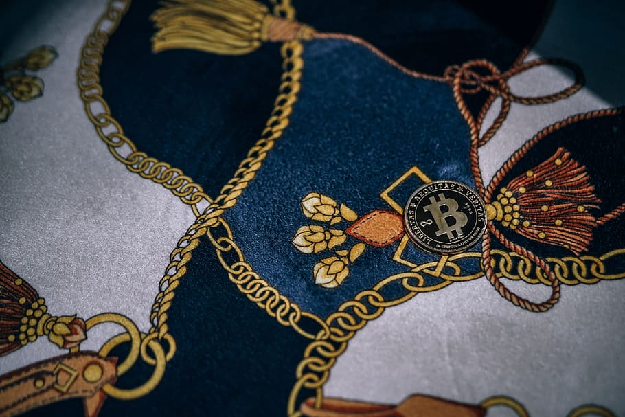 Physical Gold-Plated Bitcoin Placed on a Fabric with Gold Chain Pattern. HD wallpaper