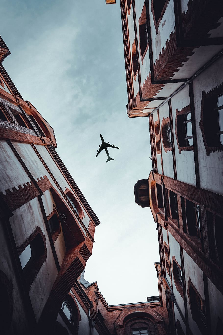 airplane over white buildings, office building, vehicle, transportation