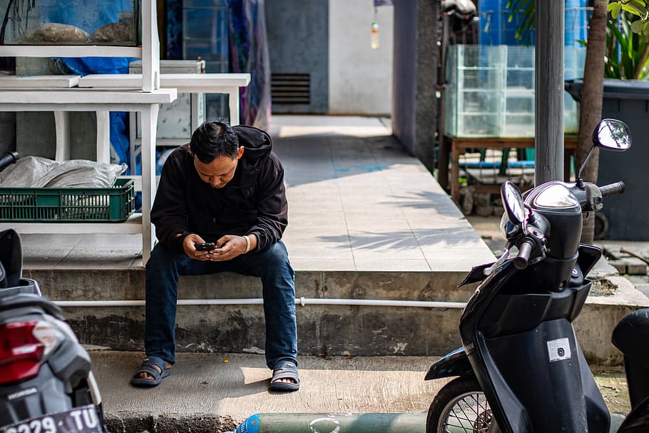 man sitting on pavement near motorcycles, clothing, apparel, shoe