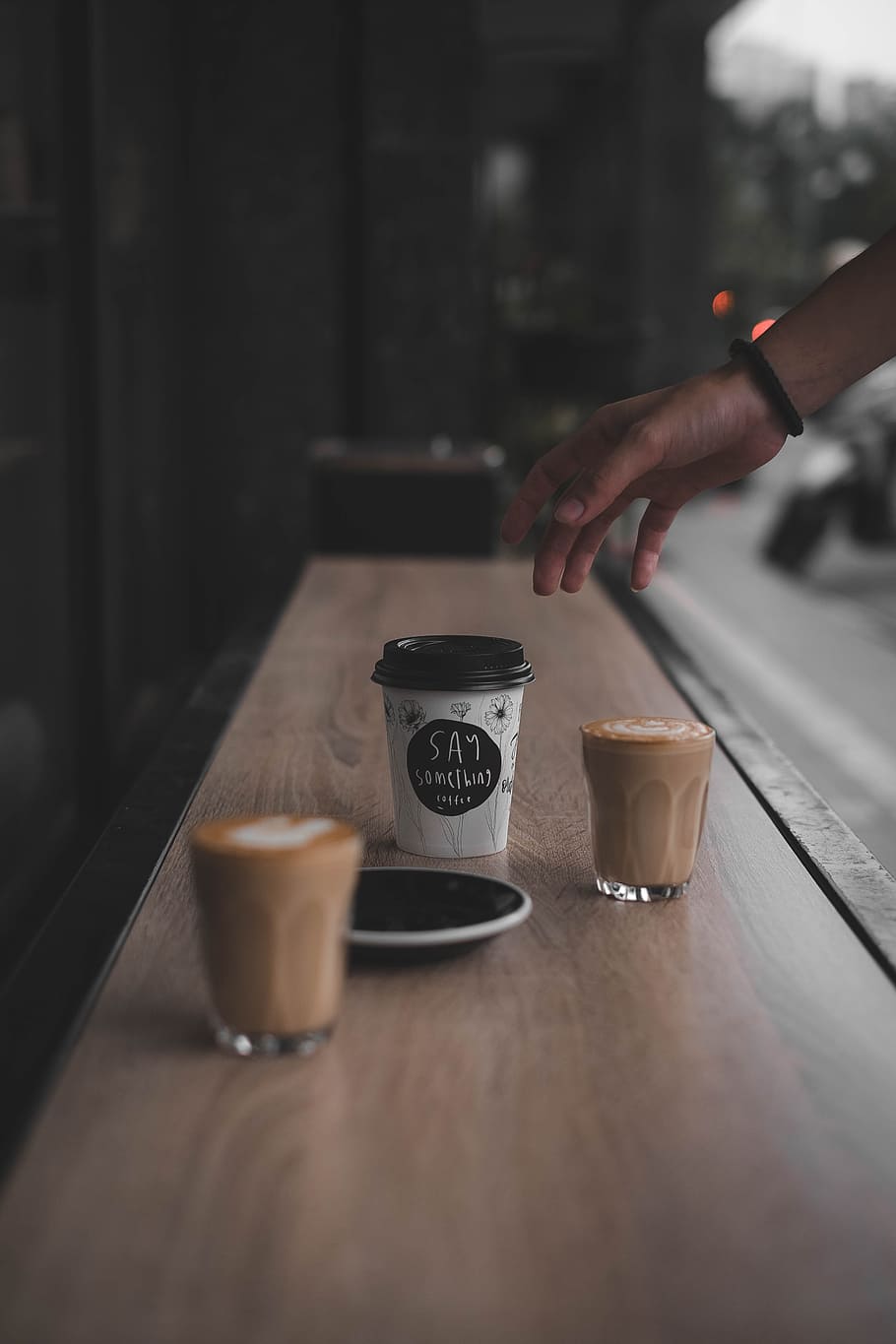 person reaching coffee cup beside glass on brown surface, take HD wallpaper