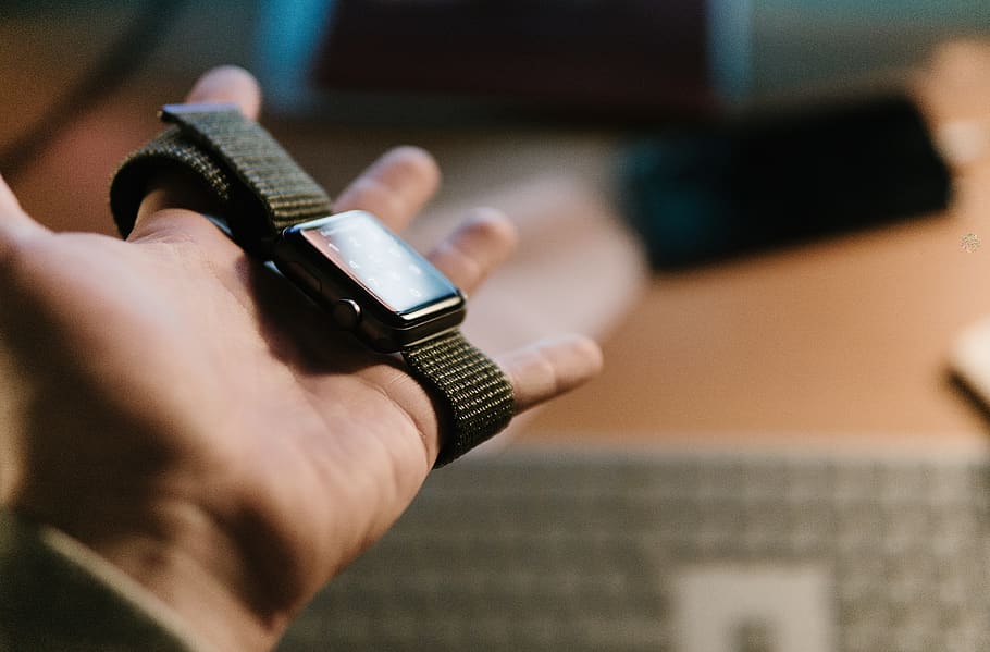 person holding Apple watch on selective focus photography, finger