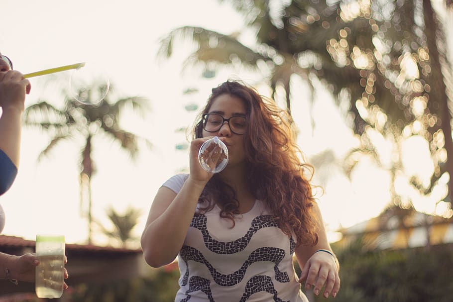 Photo of Woman Blowing Bubbles, blur, curly hair, depth of field
