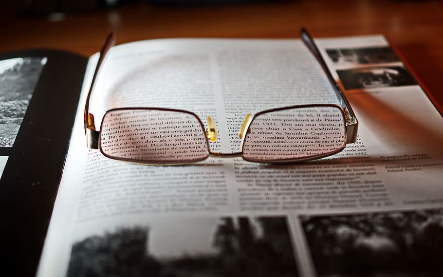 Eyeglasses With Gold-colored Frame on Opened Book, book pages