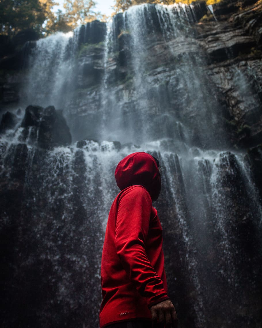 man in hooded jacket standing in front of waterfalls, person HD wallpaper