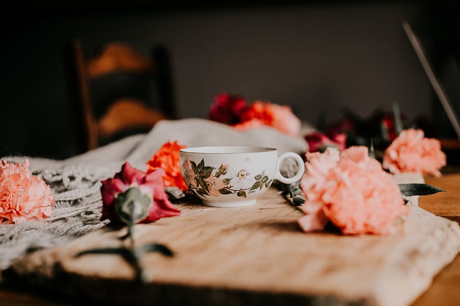 On table there is flower. Цветы возле кружки фото.