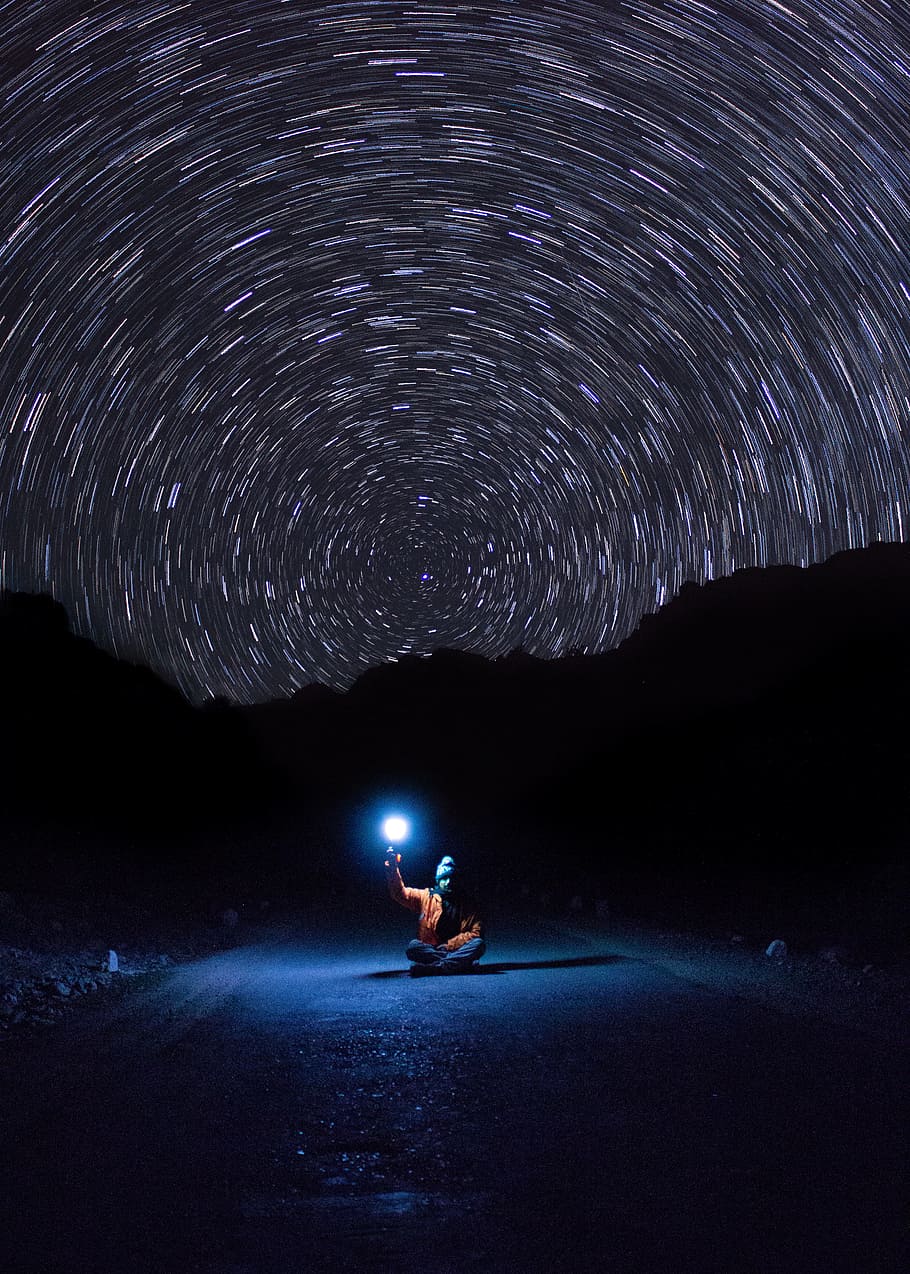 photo of person sitting on pave road holding light, galaxy, long exposure HD wallpaper