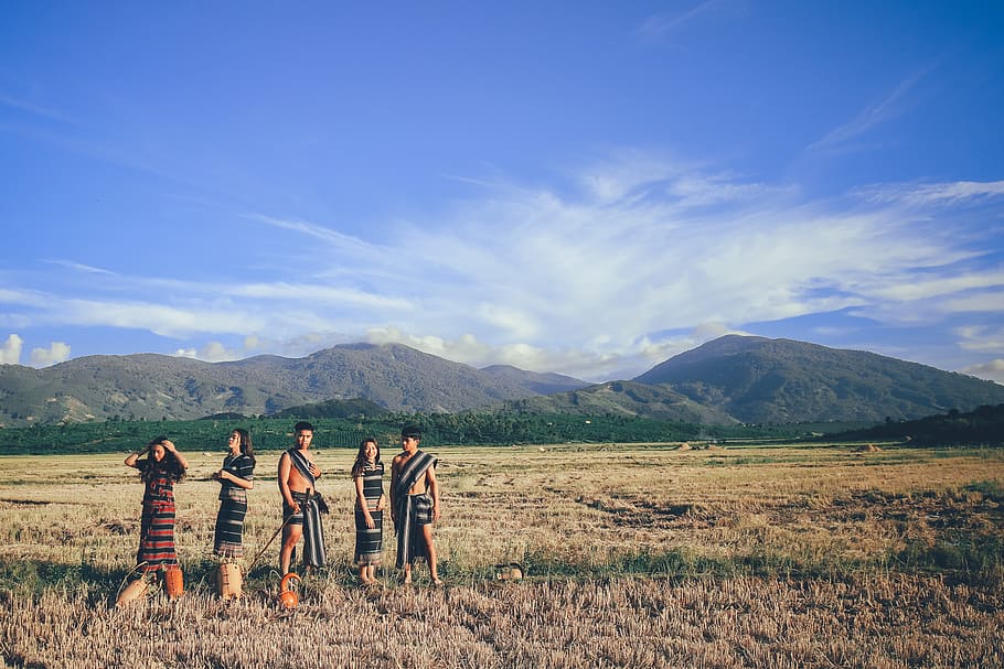 Five People Wearing Native Apparel Standing on Brown Grassfield Under Blue and White Cloudy Sky HD wallpaper