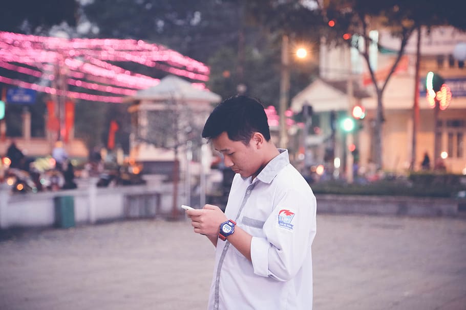 Focus Photography of Man Wearing White Sports Shirt Holding Smartphone Near Buntings HD wallpaper