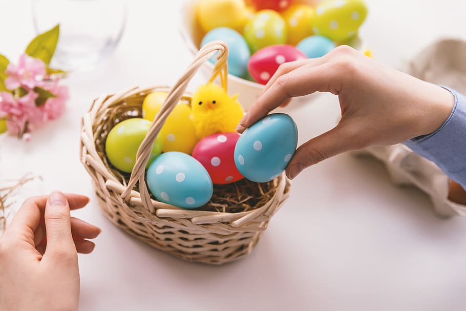 Happy Easter! Young woman is giving painted eggs to basket, multi colored HD wallpaper