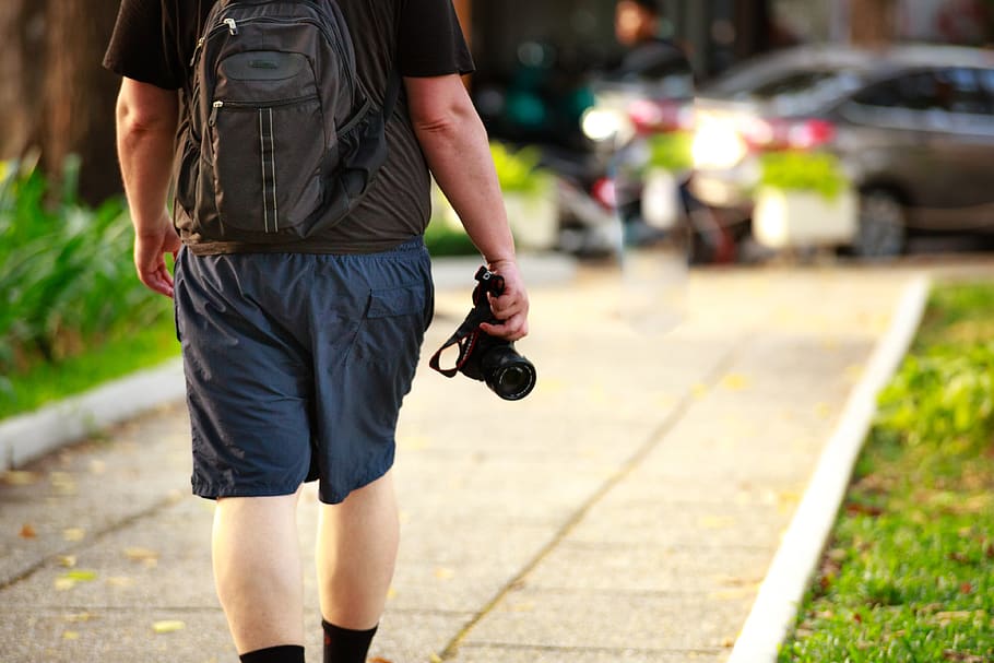 Man Holding Black Camera, backpack, casual, gadget, grass, leisure HD wallpaper