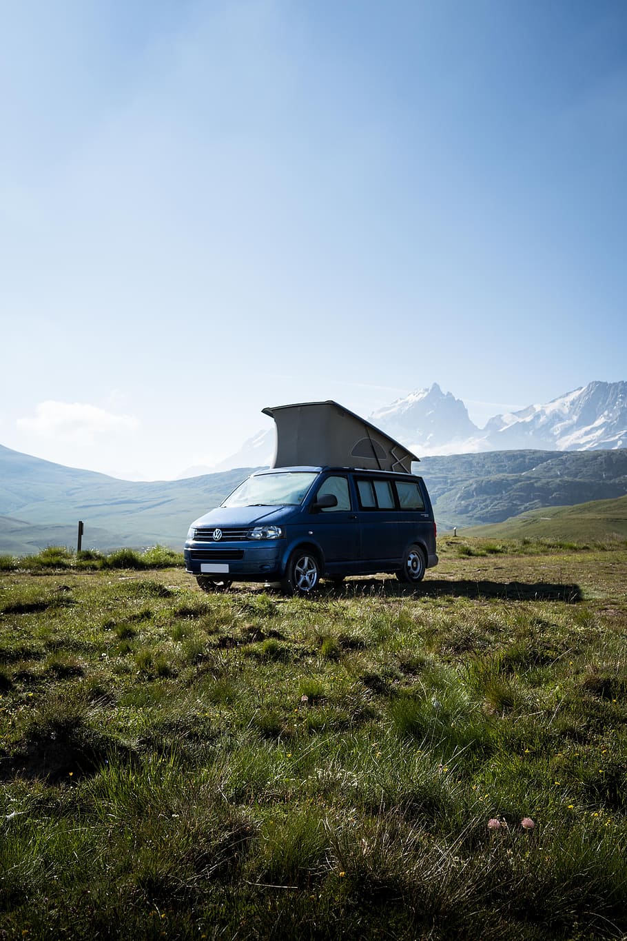 blue Volkswagen Transporter van on green grass field, camp, parked