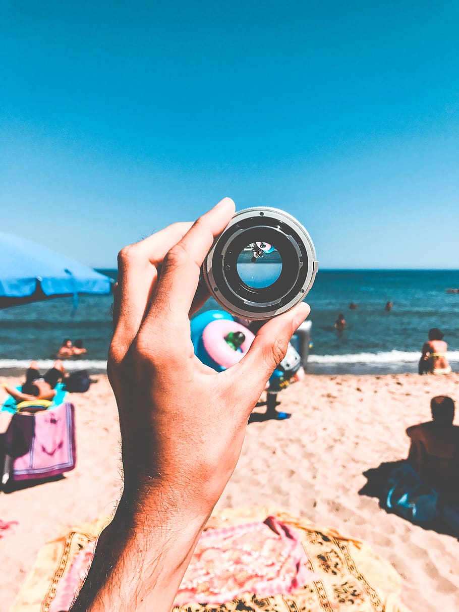 Person Holding Camera Lens, beach, daytime, hand, looking, ocean HD wallpaper