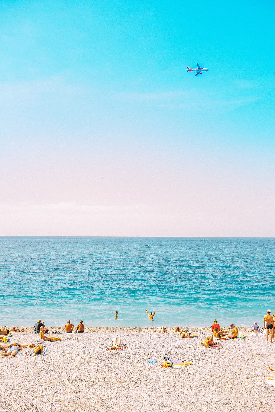 people sunbathing on sea shore under white and blue sky at daytime HD wallpaper
