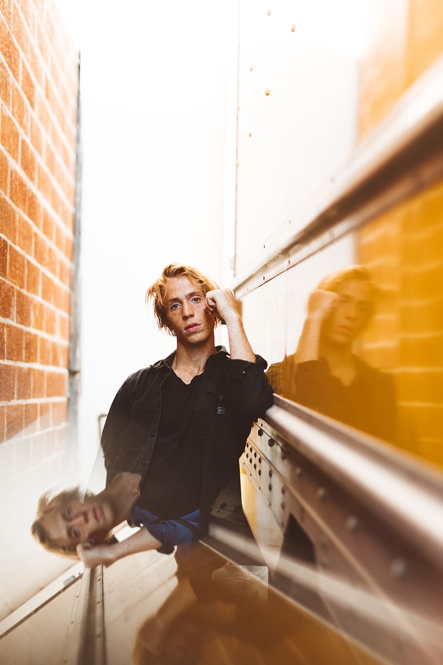 shallow focus photo of man in black jacket standing beside brown brick wall, HD wallpaper