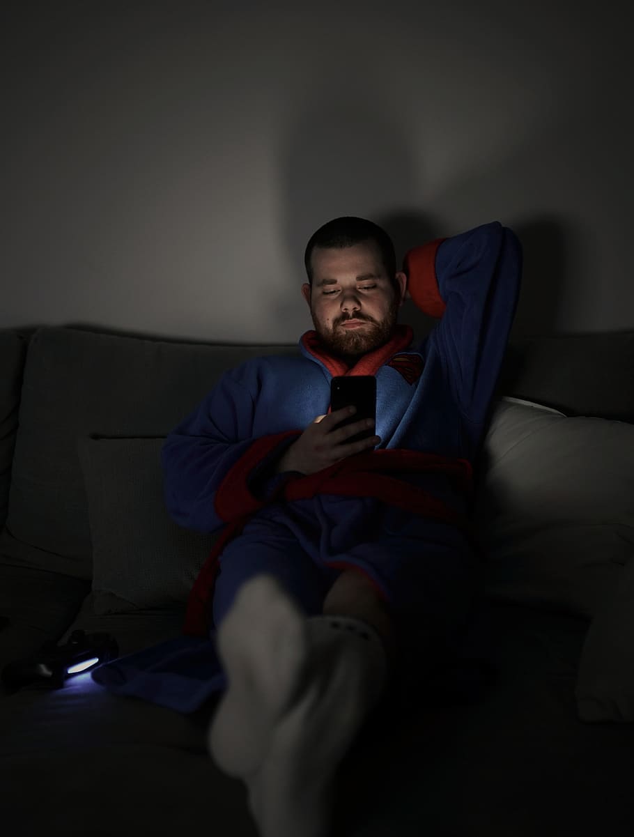 man sits on sofa while using smartphone, couch, furniture, human HD wallpaper