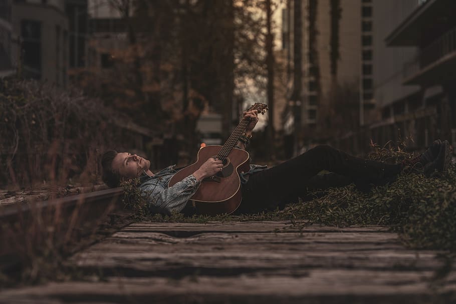 Man Lying Down on Ground While Playing Guitar, daylight, fashion model