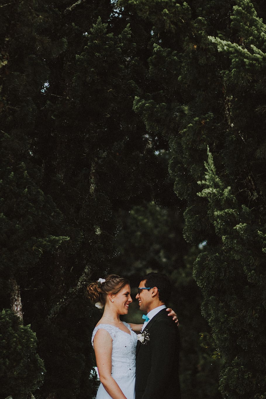 smiling woman standing near smiling man and putting her hand on back of man near green trees HD wallpaper