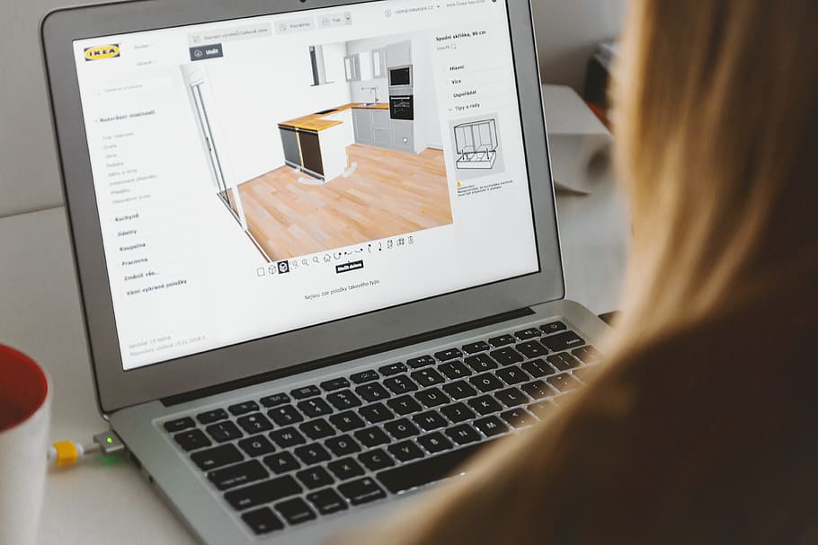Woman uses 3D planning software for her new kitchen on laptop at home HD wallpaper