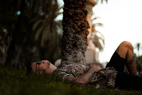 man in brown shirt lying on green grass, looking up, laying down HD wallpaper