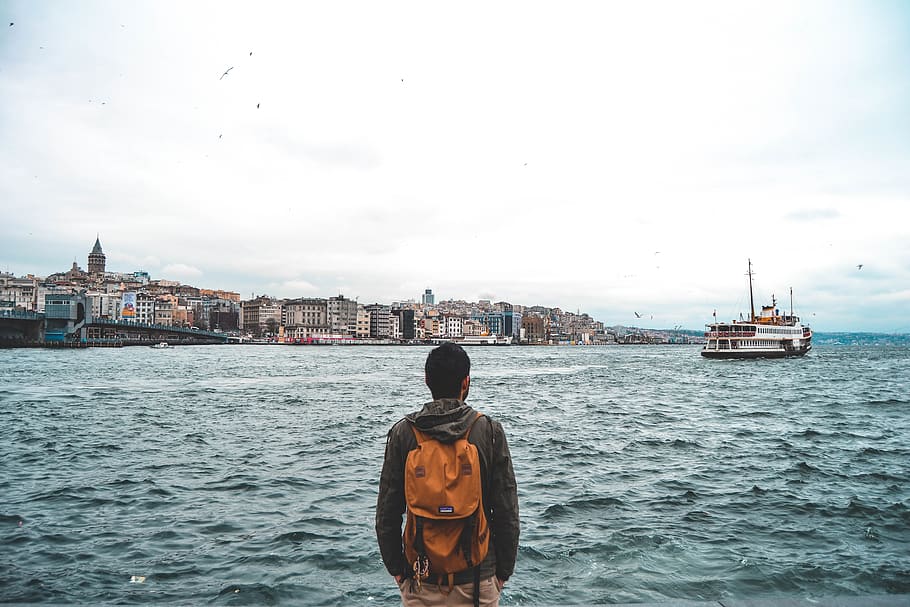 Man Looking at the City, backpack, buildings, daylight, ocean HD wallpaper