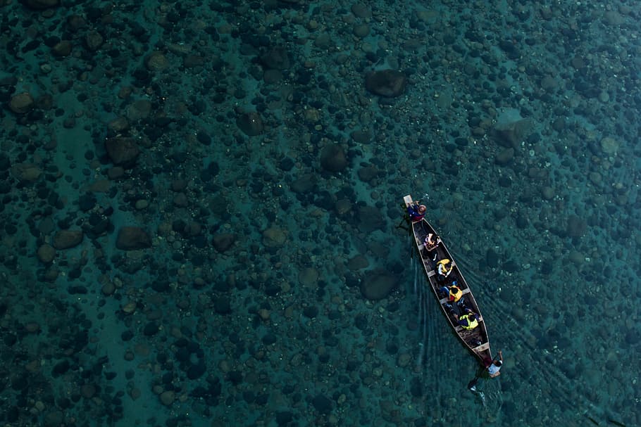 aerial photo of canoe on calm water with people, aerial view