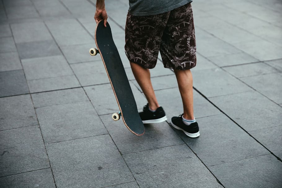 Skateboarder wearing shorts and sneakers getting ready to skate