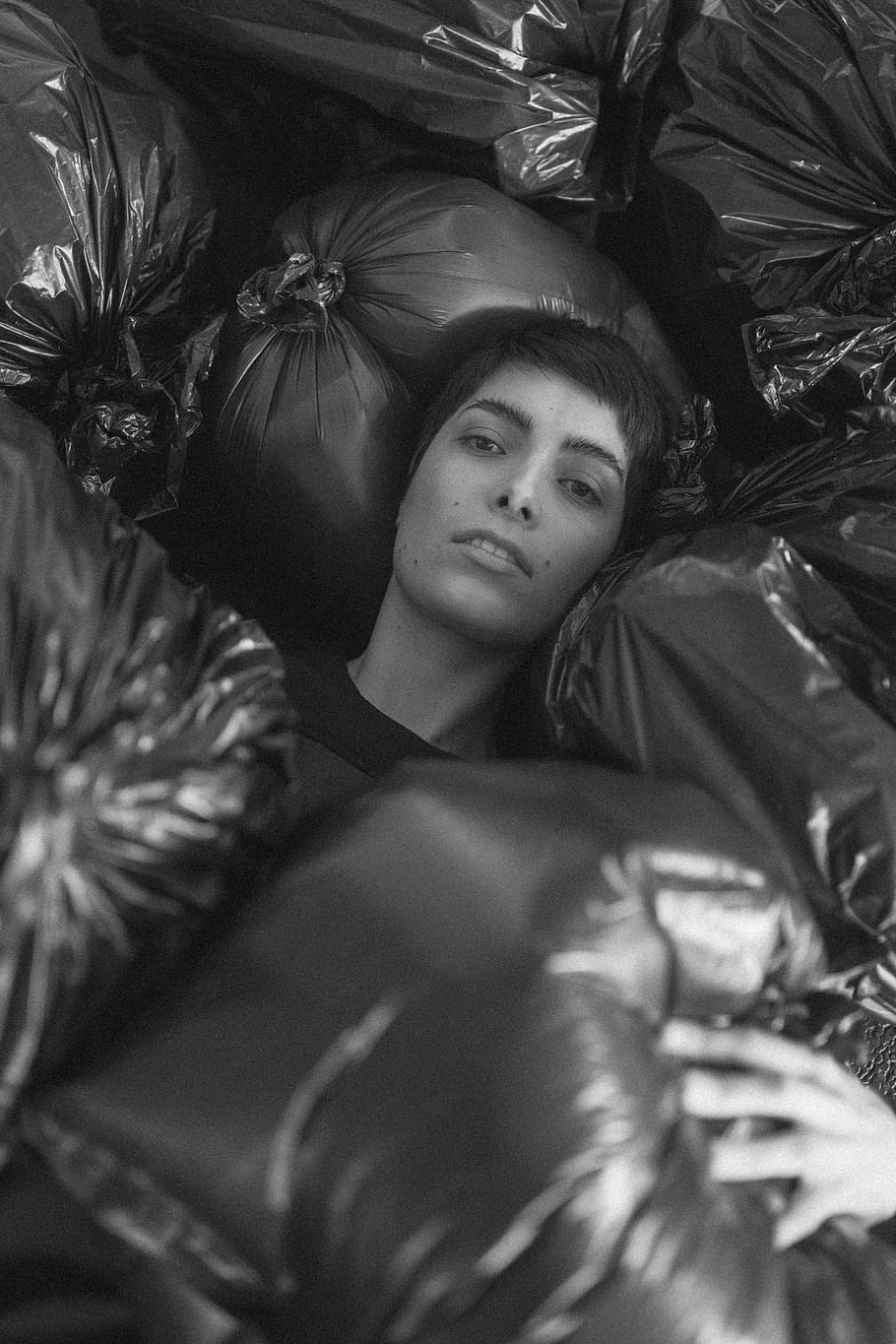Grayscale Photo of Female Surrounded by Black Plastic Bags, adult