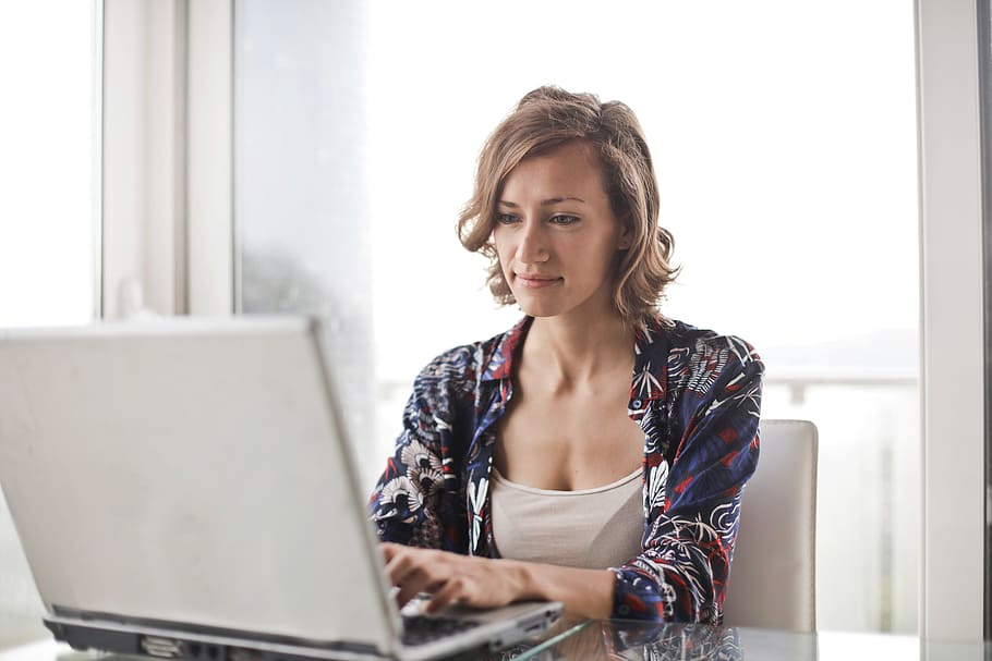 A young blonde woman working on her laptop in the office during the day time HD wallpaper