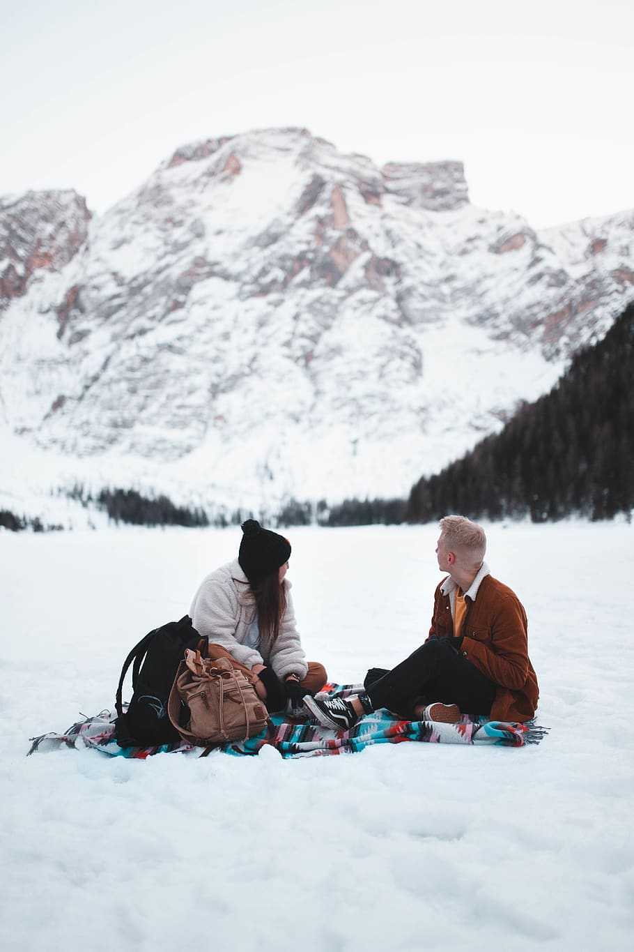 man and woman sitting in middle of snow field during daytime HD wallpaper