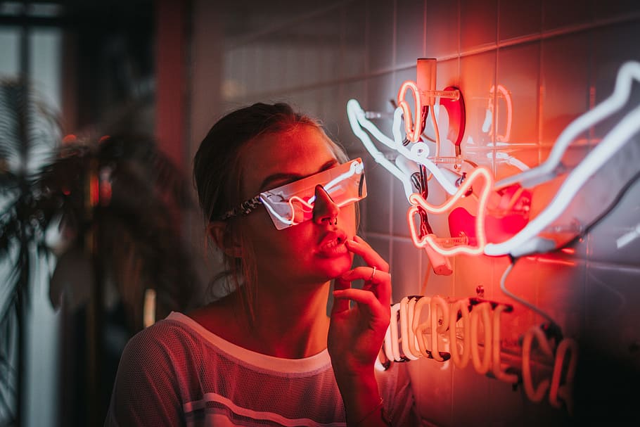 woman standing beside lighted neon lights, portrait, sunglasses