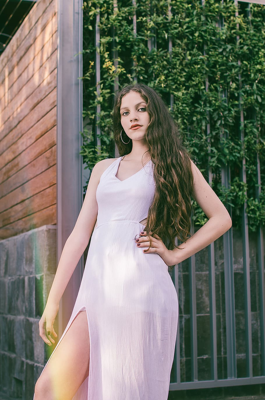woman in white sleeveless side slit dress near fence, human, person
