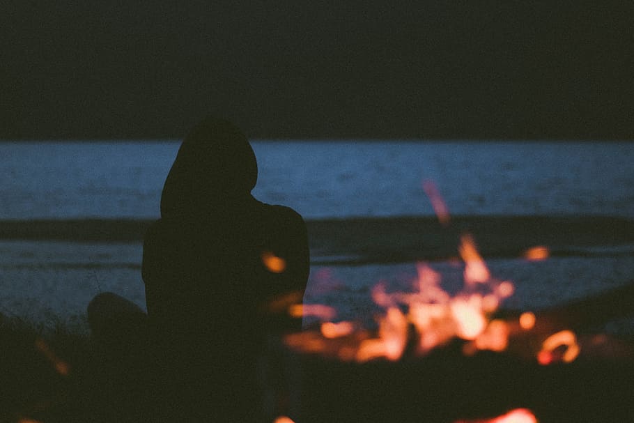 silhouette of woman sitting on seashore near bonfire, night, burning HD wallpaper