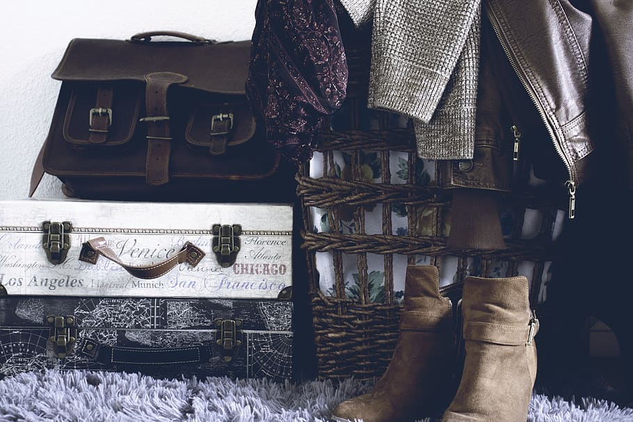 pair of brown suede boots near wicker basket and travel luggages