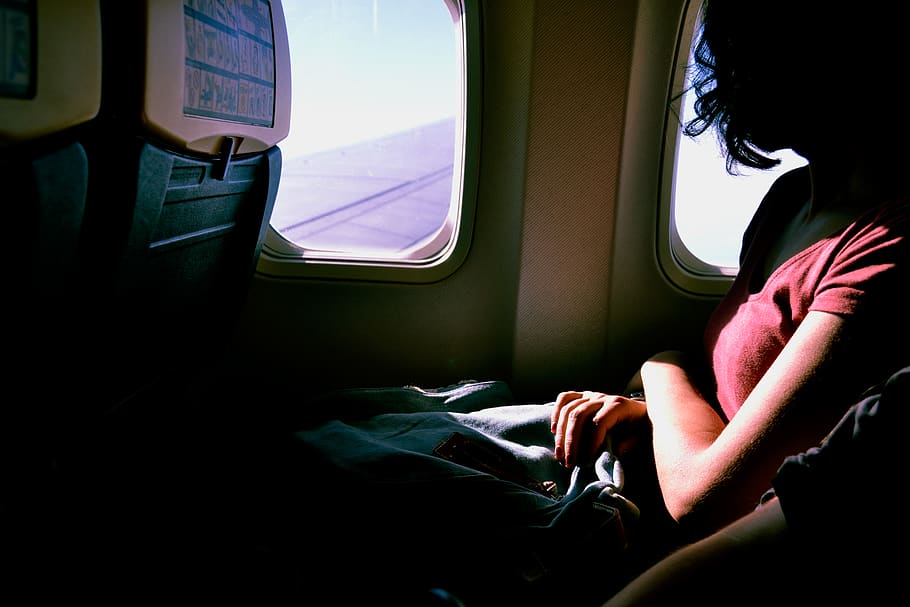 woman riding in airplane while watching at window, vehicle interior