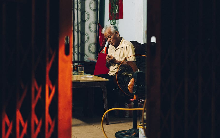 man sitting beside table inside room, real people, one person HD wallpaper