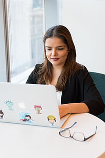 Woman Wearing Black Suit Jacket Using White Macbook With Stickers on White Wooden Table HD wallpaper