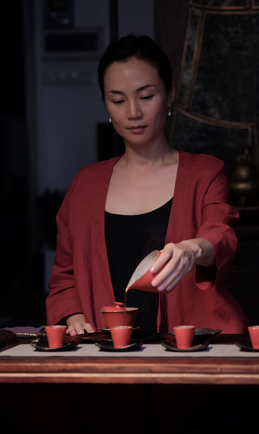 Crop view of female holding porcelain teapot and pouring hot tea into red  ceramic polka-dotted?