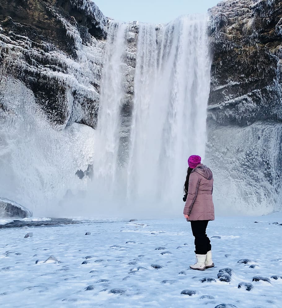 Woman Wearing Pink Snow Coat Standing on Field Full of Snow in Front of Frozen Waterfalls HD wallpaper