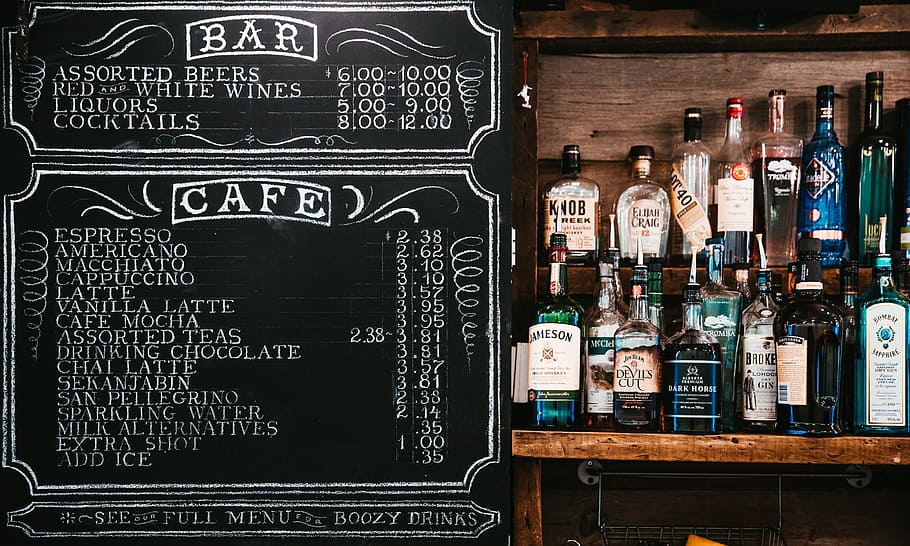 Chalkboard menu at a bar counter alongside liquor display, alcohol