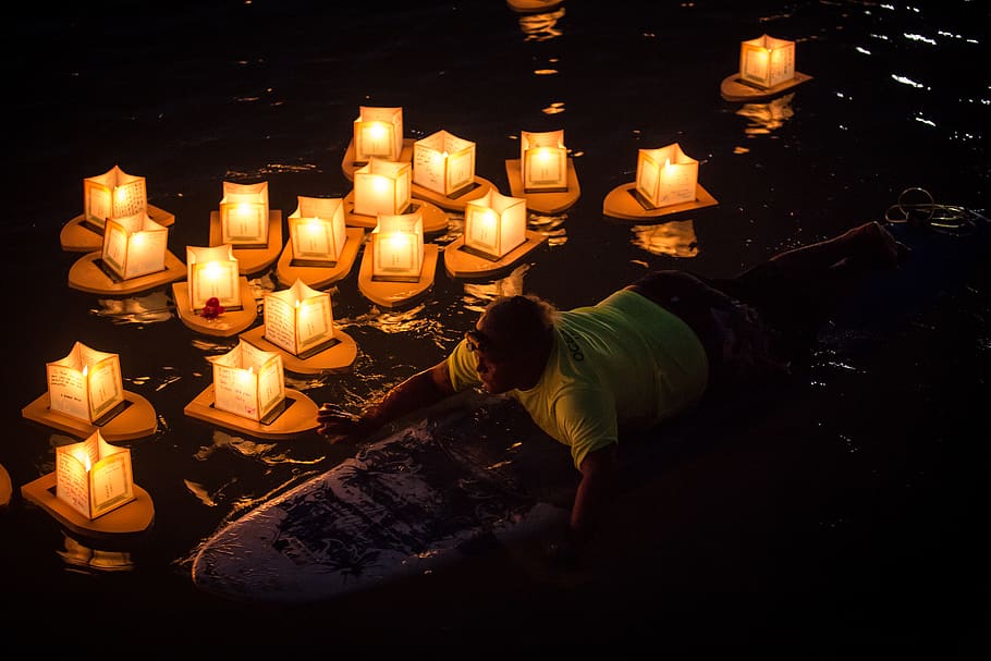 Man Rides on Surfboard Near Paper Lanterns on Body of Water during Nighttime HD wallpaper